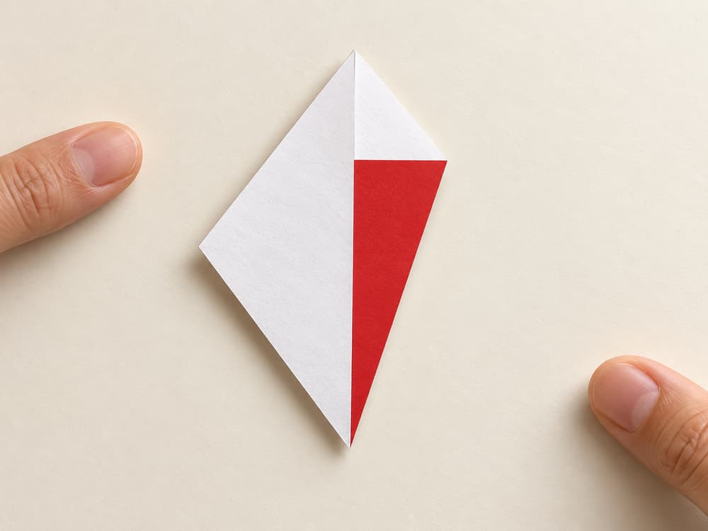 origami santa step 2: bring the lower-right sloping edge to the upright center crease, hands visible