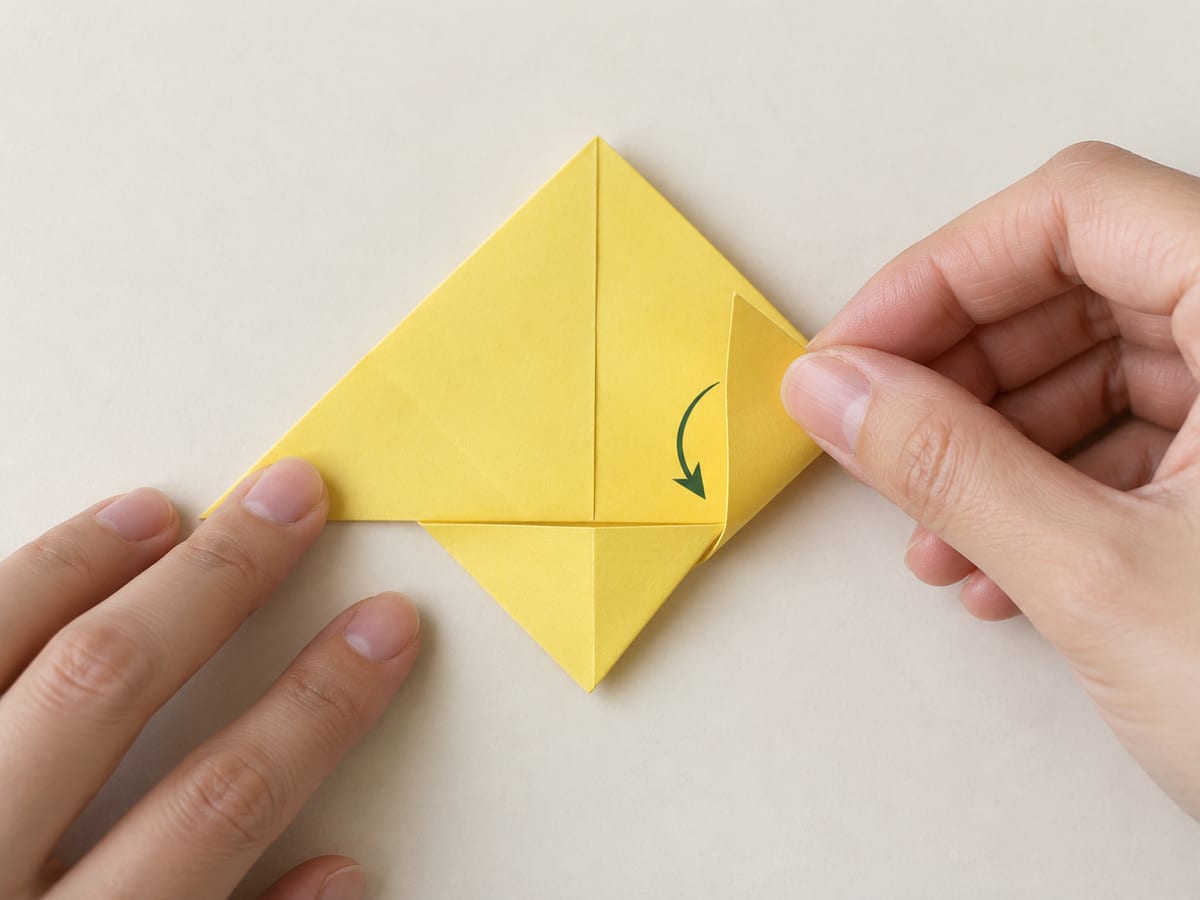 origami bookmark step 5: lift the right corner along its crease and tuck its tip behind the folded front flap, hands visible