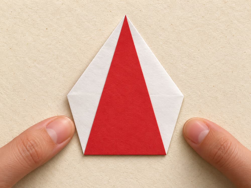 origami santa step 4: fold the lower point all the way up to the top point, hands visible