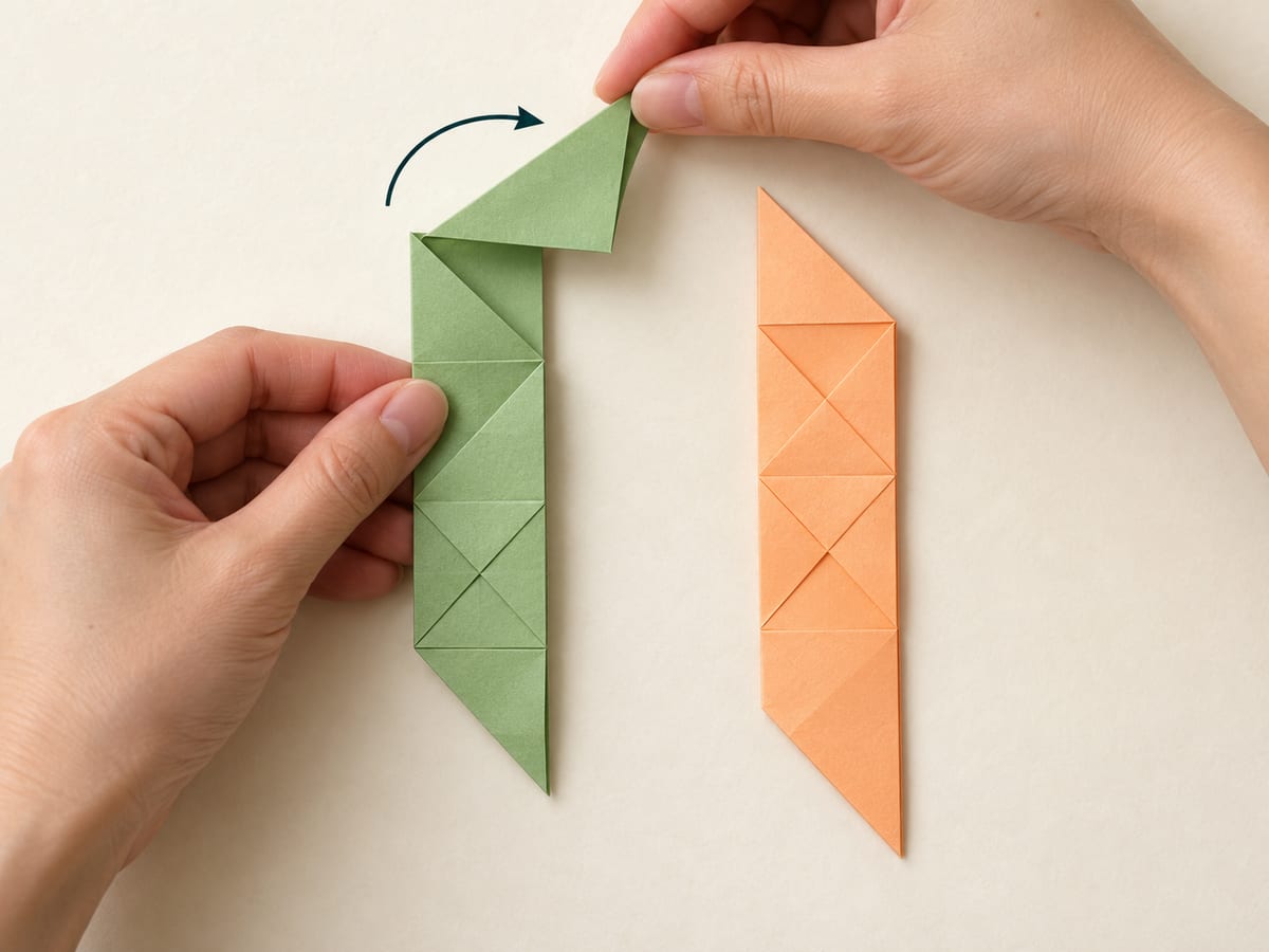 origami ninja star step 6: fold the upper half of the first strip diagonally rightward at its midpoint, hands visible