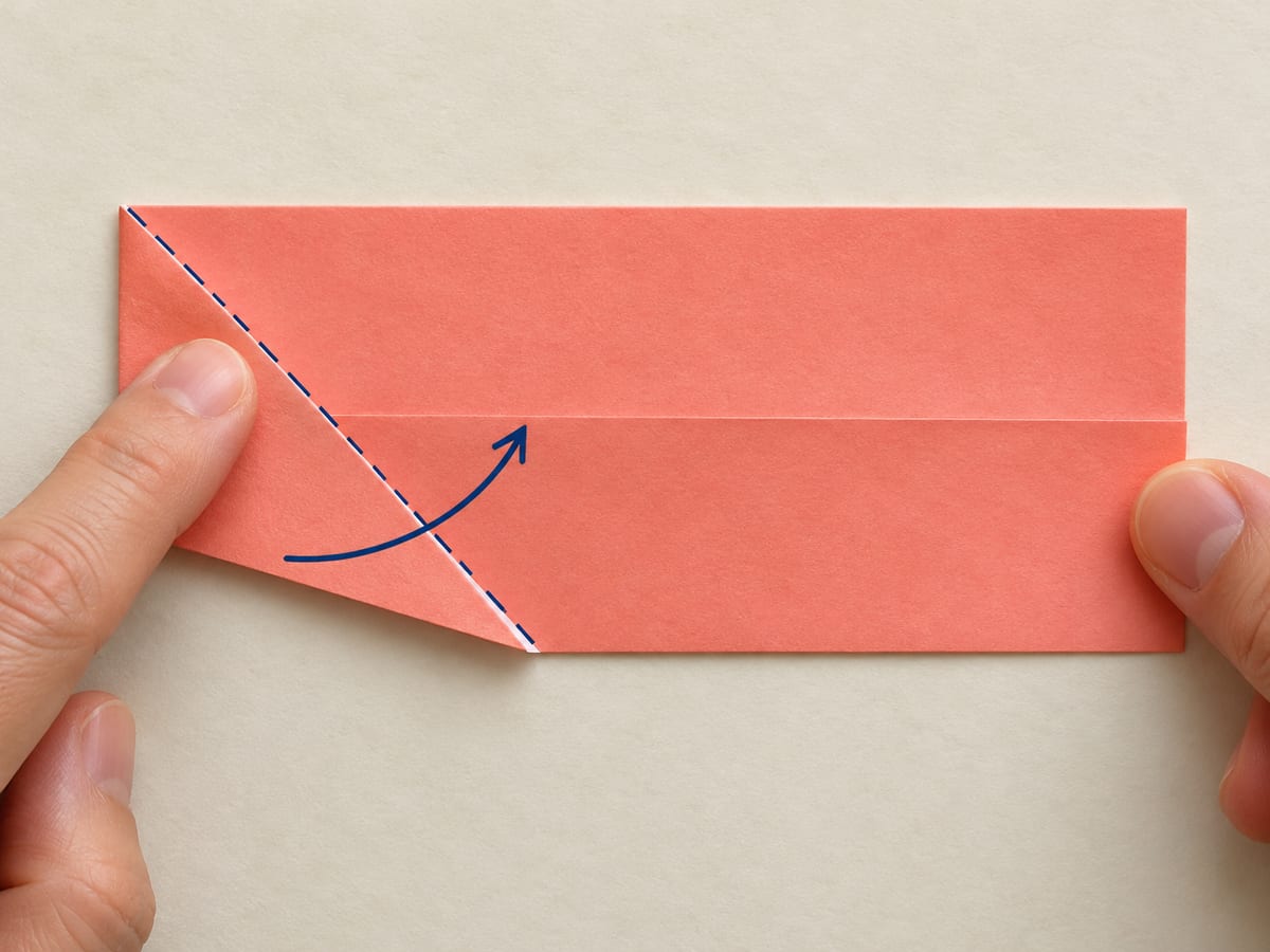 origami star step 2: bring the lower-left corner to the center crease while the fold starts at the upper-left corner, hands visible