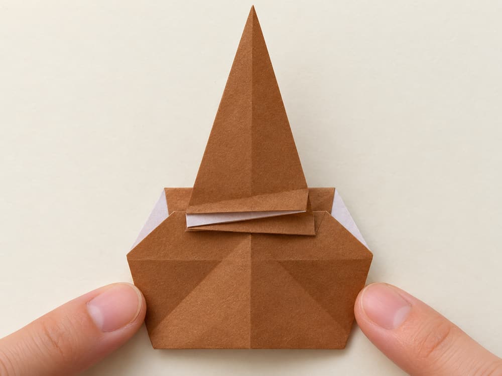 origami turkey step 5: fold that point upward, leaving a narrow pleat at the bottom, hands visible