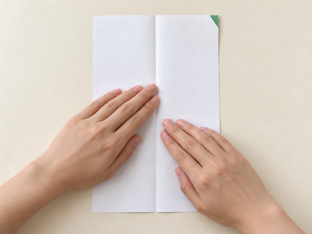 origami frog step 1: place the rectangle upright; fold the long edges together, crease, and reopen, hands visible