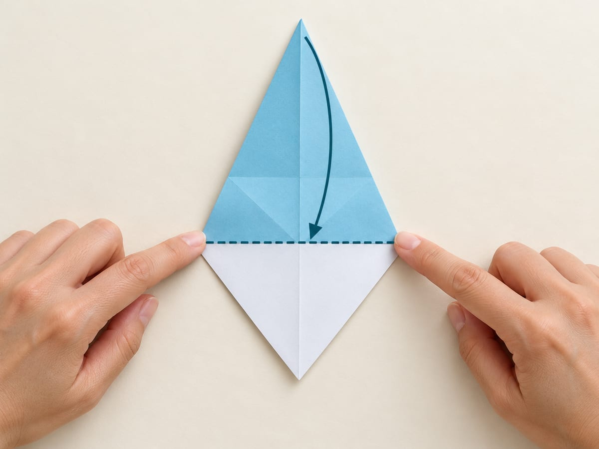 origami shark step 6: bring the narrow top tip to the bottom edge of the folded flaps, hands visible