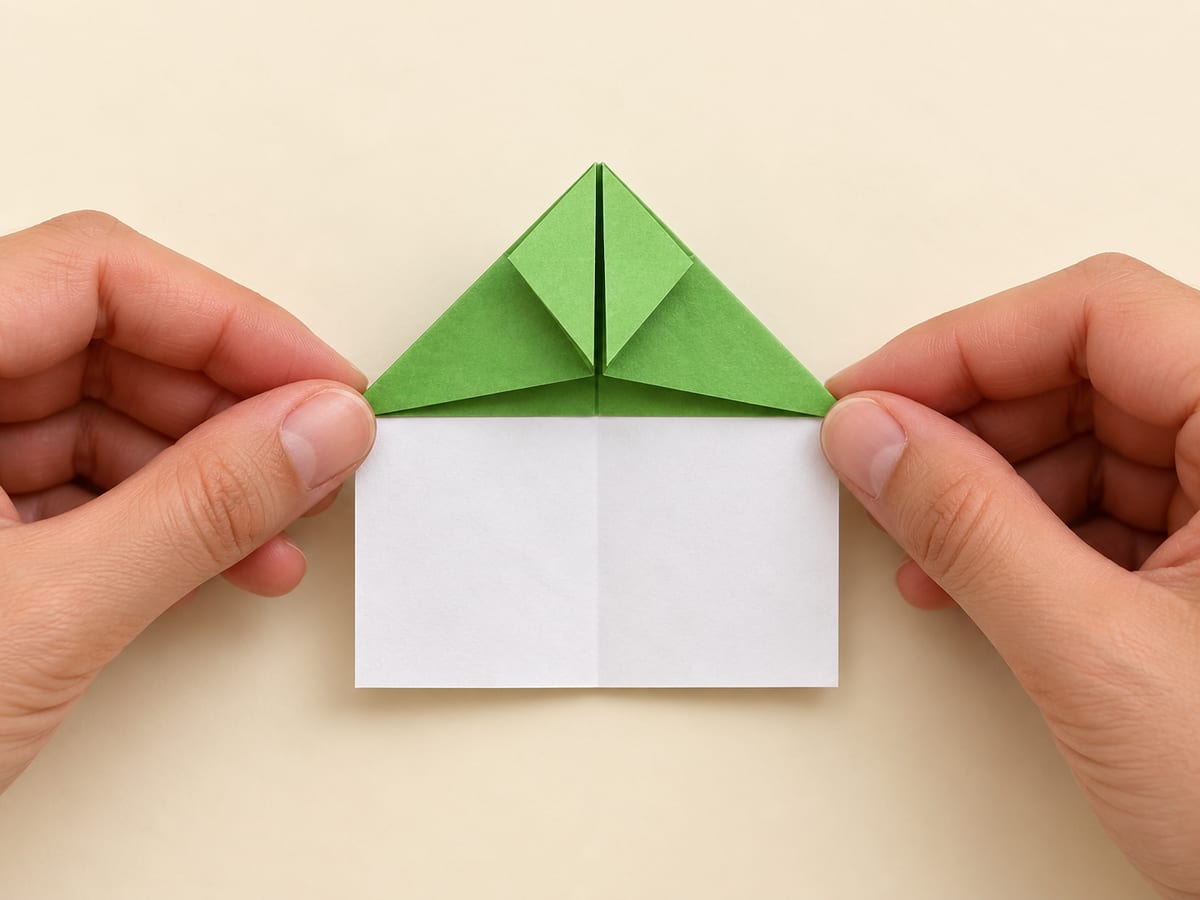 origami frog step 7: fold the matching right corner upward to make the second front leg, hands visible