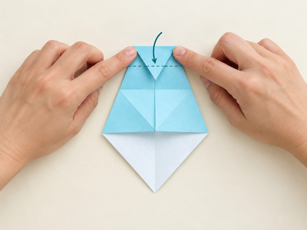 origami shark step 7: fold the narrow top tip to the crease from step 5 and reopen, hands visible