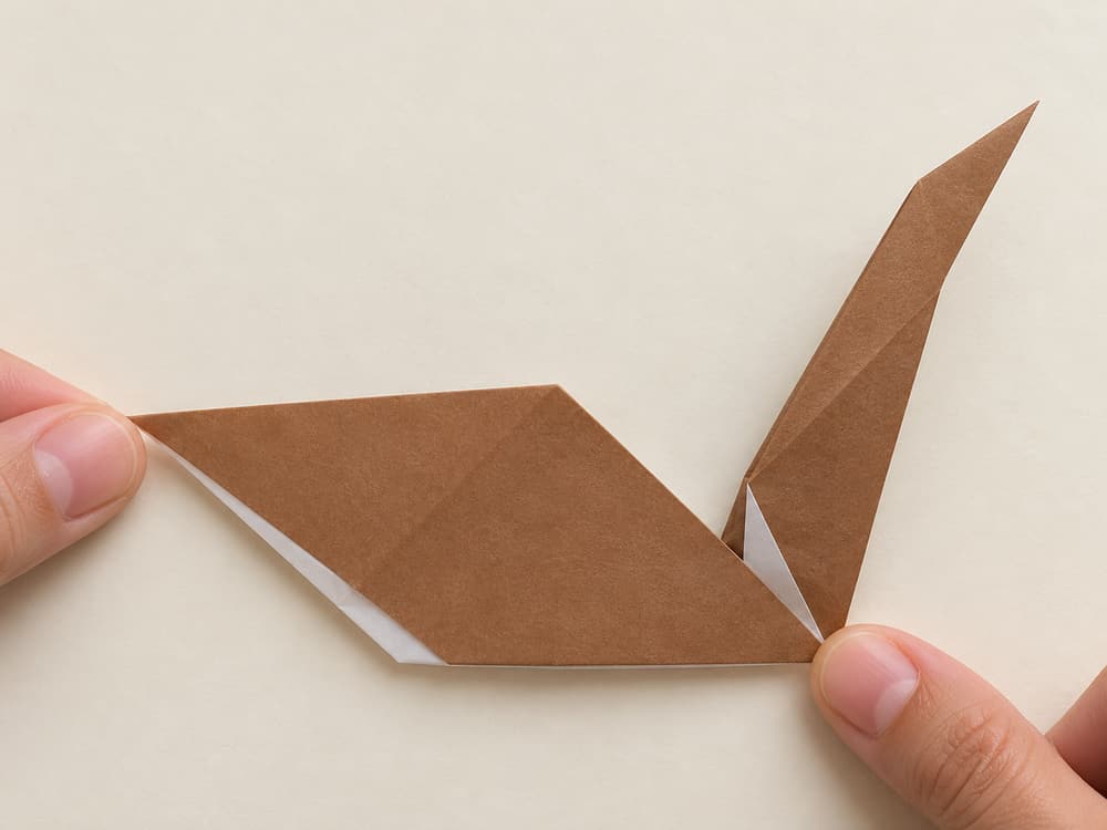 origami turkey step 7: pull the narrow neck upward from the body and pinch its base to hold the angle, hands visible