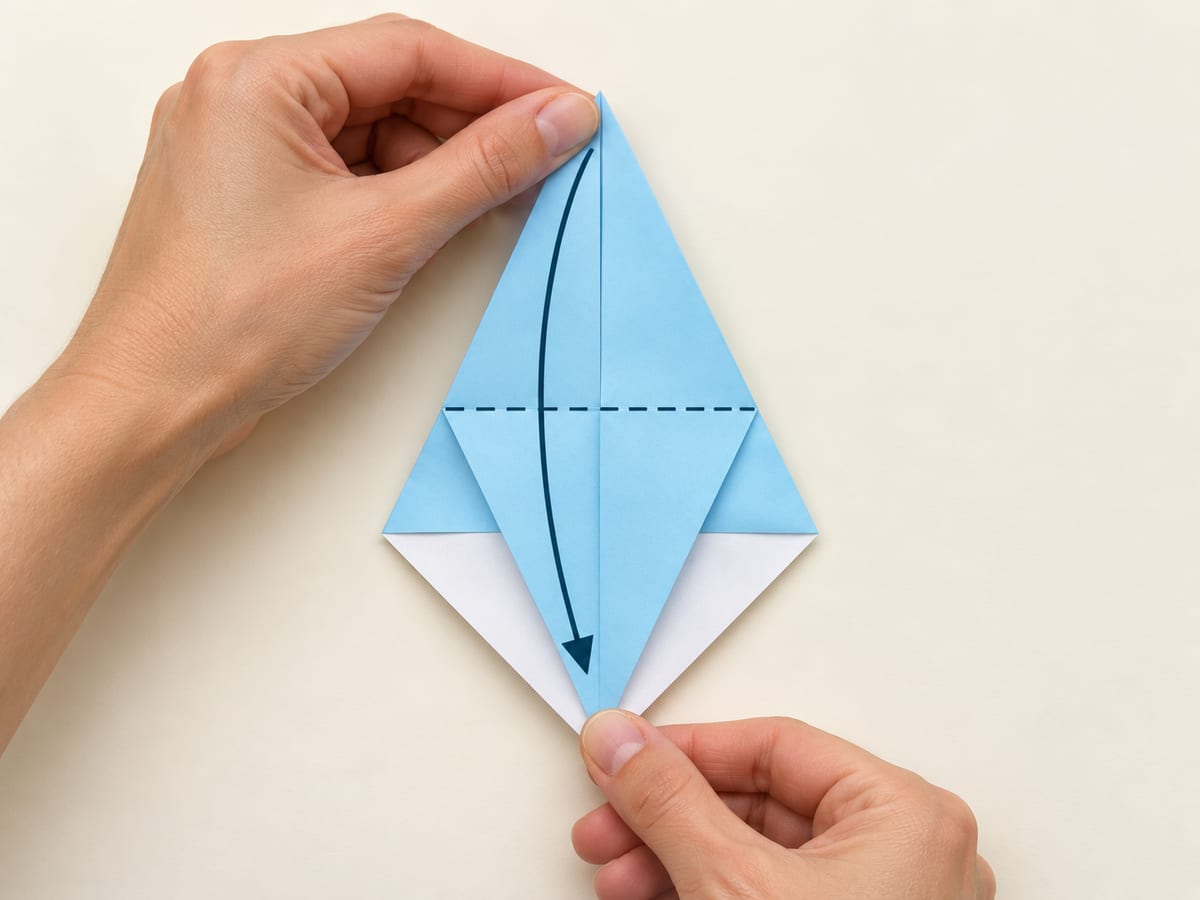 origami shark step 5: bring the narrow top tip to the bottom tip and reopen the kite, hands visible